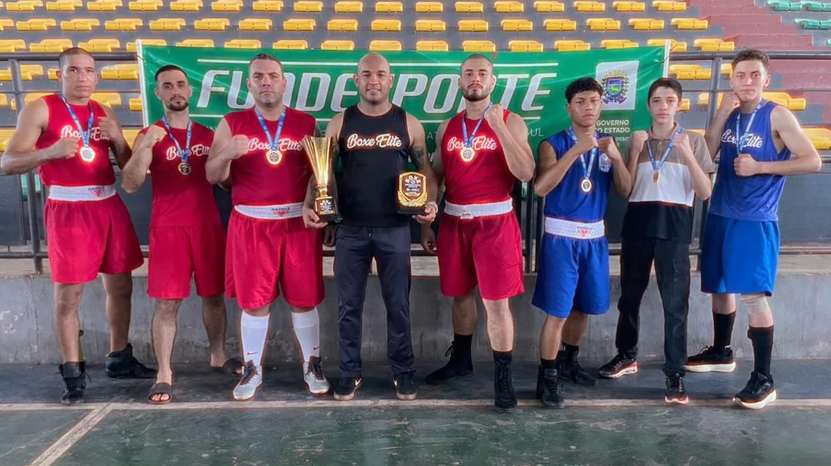 Atletas da Boxe Elite com medalhas e o troféu de campeã, ao lado do Paulo Lima
